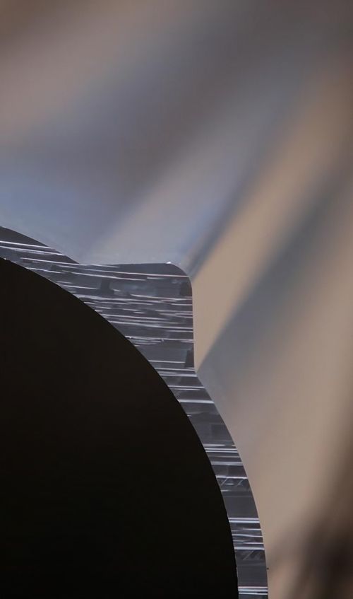 Detailaufnahme eines Metallstücks, das die Oberflächenbeschaffenheit und Reflexion des Materials hervorhebt.